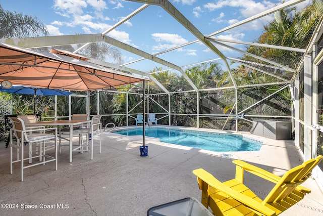 view of swimming pool with glass enclosure and a patio