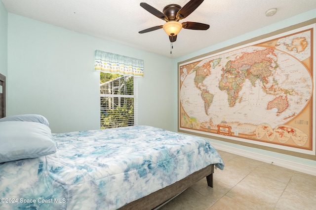 bedroom with ceiling fan, light tile patterned floors, and a textured ceiling