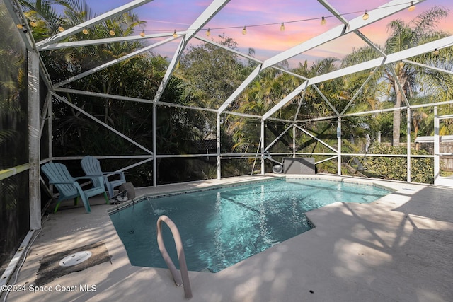 pool at dusk with a patio and a lanai