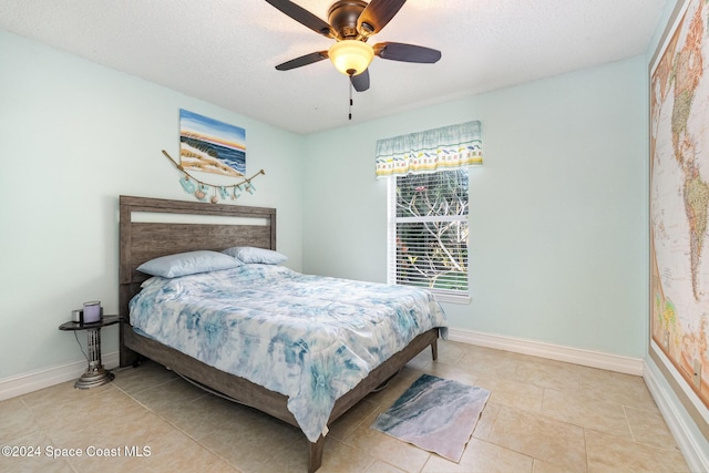 bedroom with ceiling fan, light tile patterned floors, and a textured ceiling