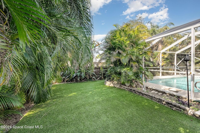 view of yard featuring a fenced in pool and glass enclosure