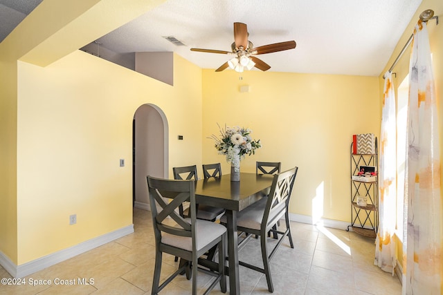 dining area with a textured ceiling, ceiling fan, light tile patterned floors, and vaulted ceiling