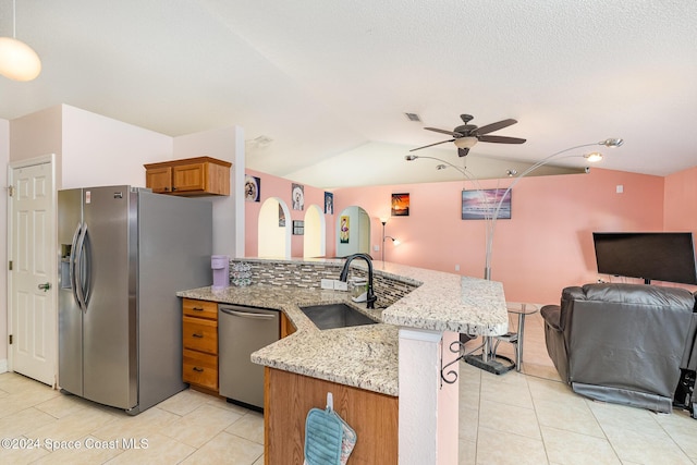 kitchen with light stone countertops, sink, ceiling fan, stainless steel appliances, and kitchen peninsula