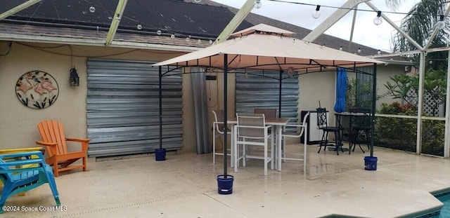 view of patio featuring a gazebo, glass enclosure, and exterior bar