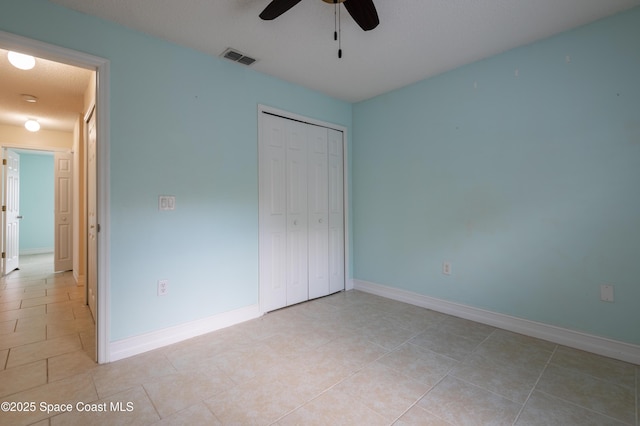 unfurnished bedroom with light tile patterned floors, a closet, and ceiling fan