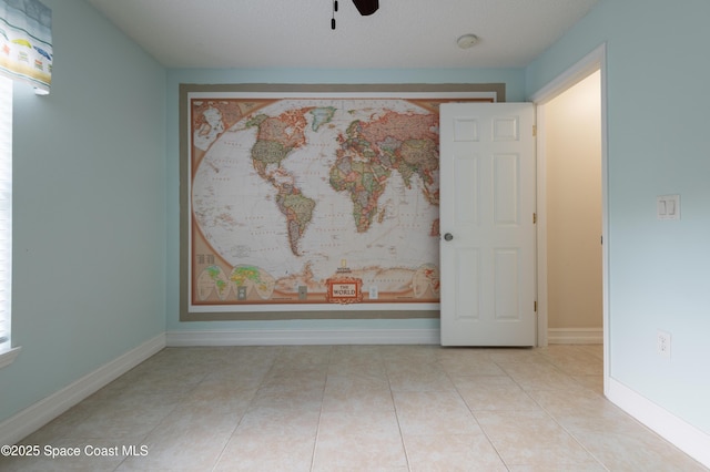 empty room with light tile patterned flooring and ceiling fan