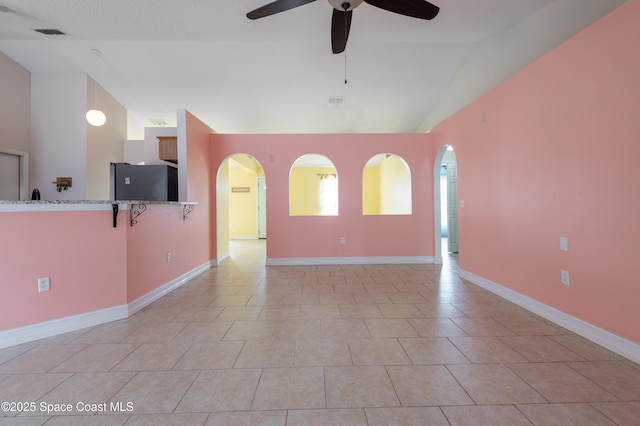 empty room featuring ceiling fan, high vaulted ceiling, and light tile patterned floors