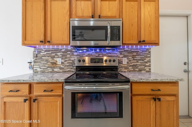 kitchen featuring light stone countertops, appliances with stainless steel finishes, and decorative backsplash