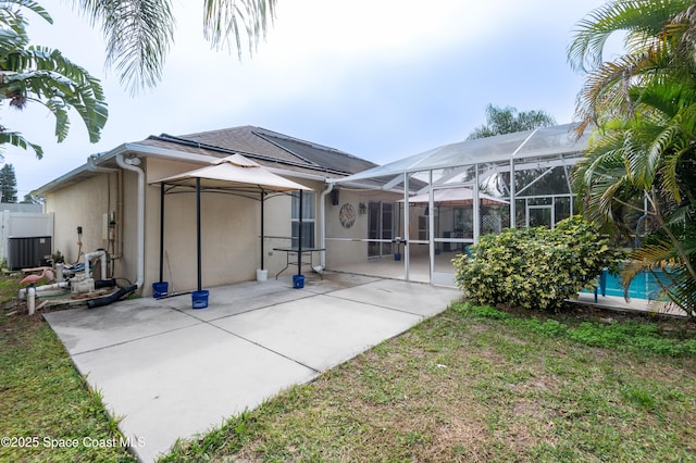 rear view of house featuring a lanai, a lawn, central air condition unit, and a patio area