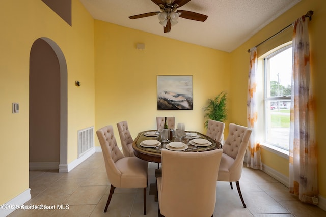 tiled dining area featuring lofted ceiling, ceiling fan, and a textured ceiling