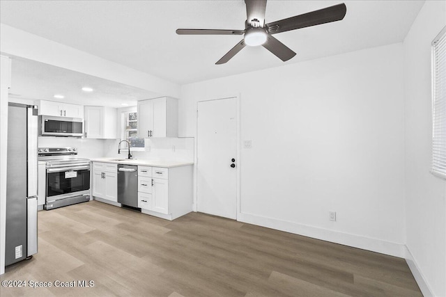 kitchen with white cabinets, sink, ceiling fan, light wood-type flooring, and appliances with stainless steel finishes