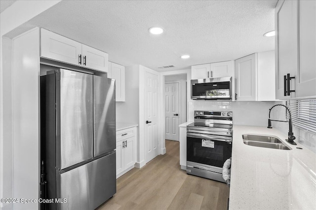 kitchen featuring white cabinets, appliances with stainless steel finishes, light hardwood / wood-style flooring, and sink