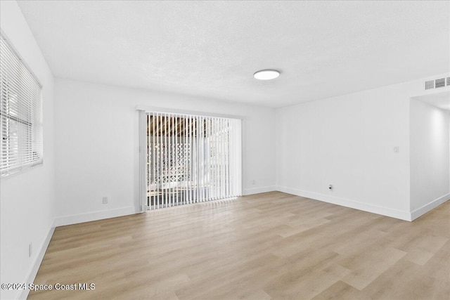 unfurnished room with plenty of natural light, light hardwood / wood-style floors, and a textured ceiling