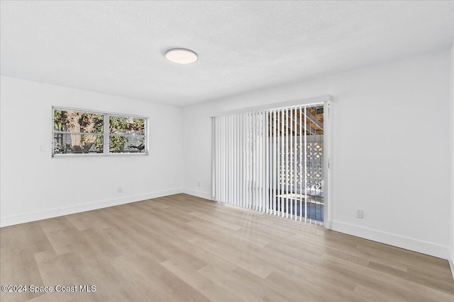 unfurnished room with a textured ceiling and light hardwood / wood-style floors