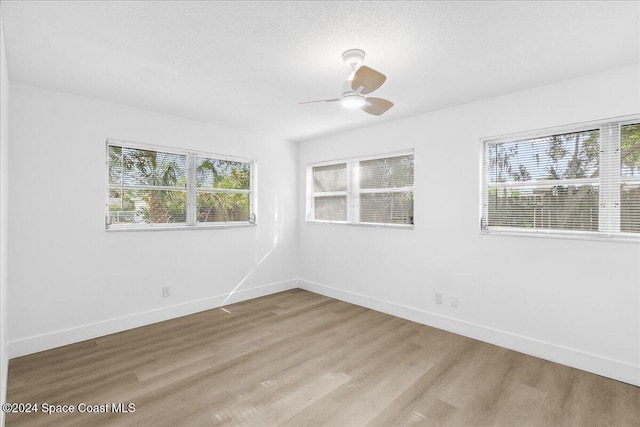 empty room featuring ceiling fan, plenty of natural light, and light hardwood / wood-style flooring