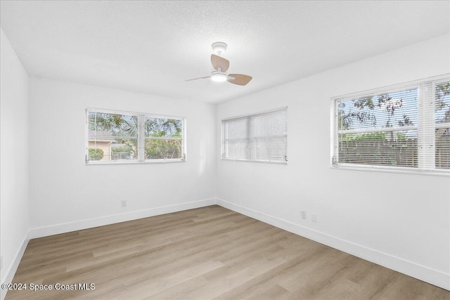 empty room with a textured ceiling, light hardwood / wood-style floors, and ceiling fan