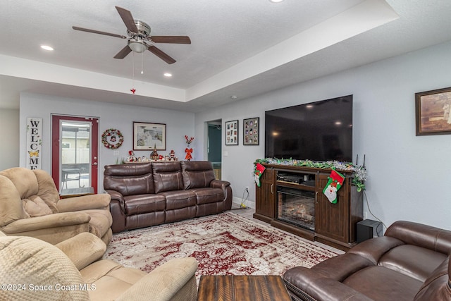 living room featuring ceiling fan and a tray ceiling