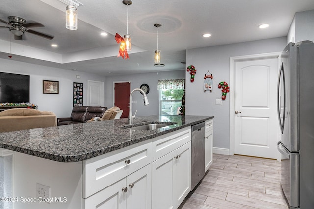 kitchen featuring sink, hanging light fixtures, a kitchen island with sink, white cabinets, and appliances with stainless steel finishes