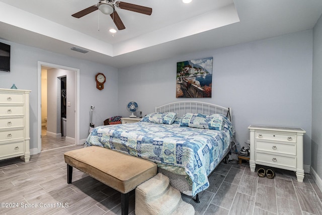 bedroom featuring a tray ceiling, ceiling fan, and light hardwood / wood-style flooring