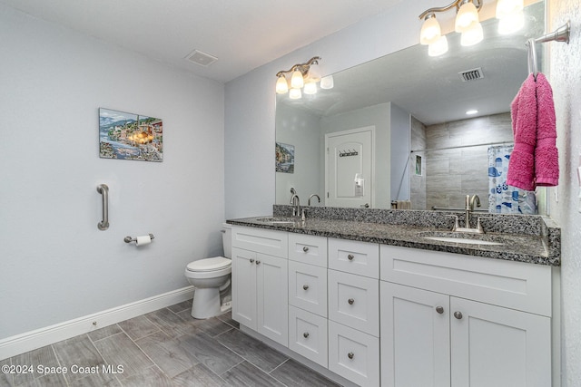 bathroom featuring a tile shower, vanity, and toilet