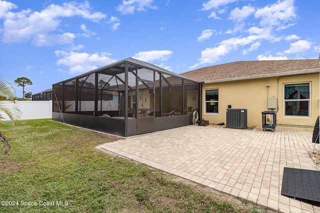 rear view of property featuring a lanai, central AC, a lawn, and a patio