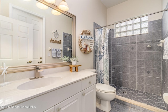 bathroom featuring tile patterned flooring, toilet, walk in shower, and vanity