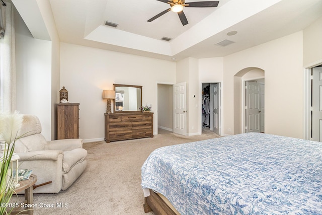 bedroom featuring light colored carpet, a closet, ceiling fan, and a raised ceiling