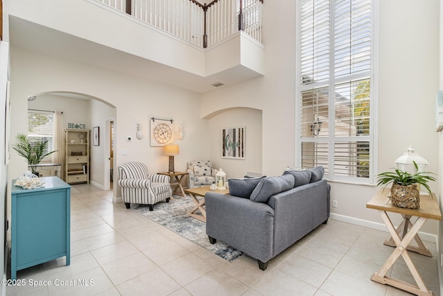 tiled living room featuring a high ceiling and plenty of natural light