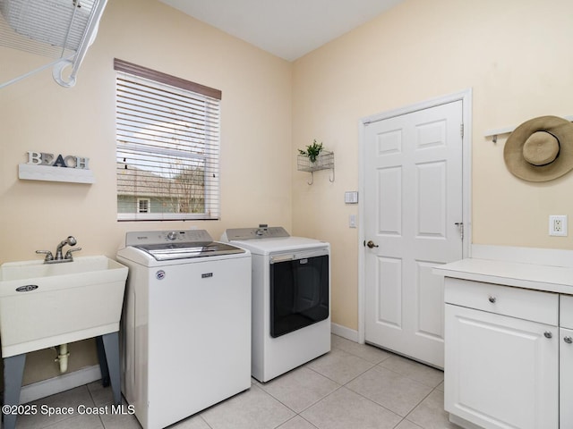 clothes washing area with sink, light tile patterned flooring, cabinets, and independent washer and dryer