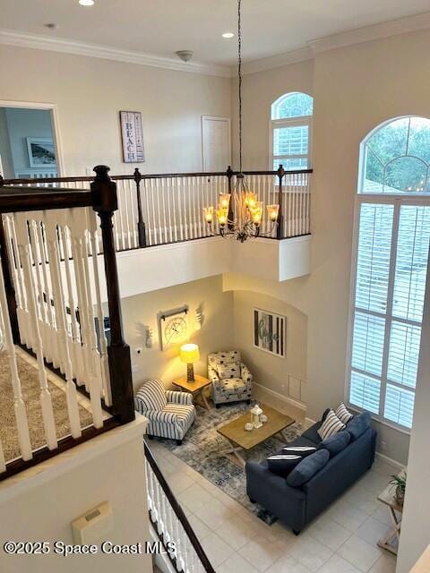 living room with a healthy amount of sunlight, crown molding, light tile patterned floors, and an inviting chandelier