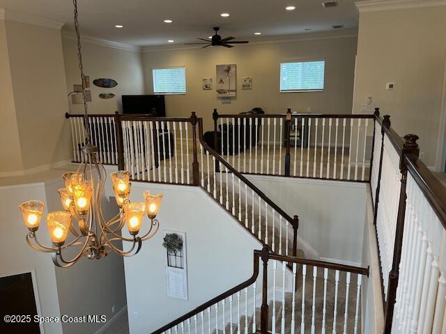 stairs with ceiling fan with notable chandelier and ornamental molding