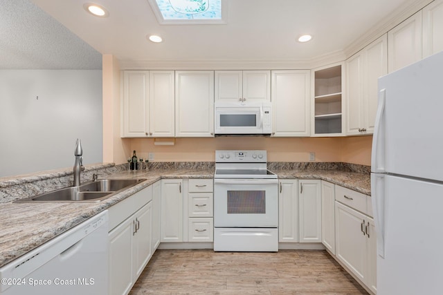 kitchen featuring light stone counters, white appliances, sink, light hardwood / wood-style floors, and white cabinetry