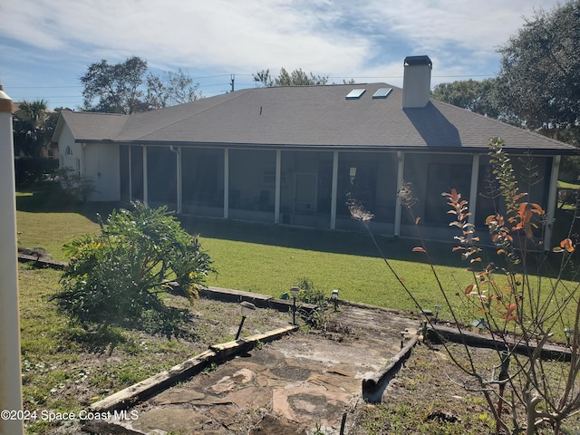 back of property featuring a sunroom and a lawn