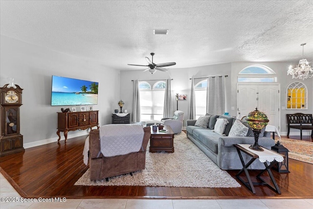 living room with wood-type flooring, ceiling fan with notable chandelier, and a textured ceiling