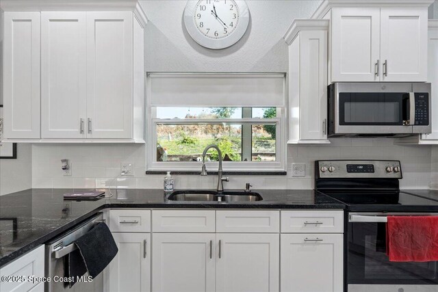 kitchen featuring sink, decorative backsplash, white cabinets, and appliances with stainless steel finishes