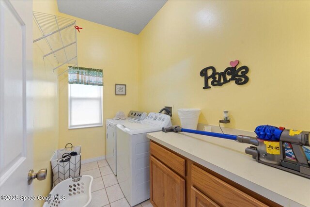 washroom with cabinets, washer and clothes dryer, a textured ceiling, and light tile patterned floors