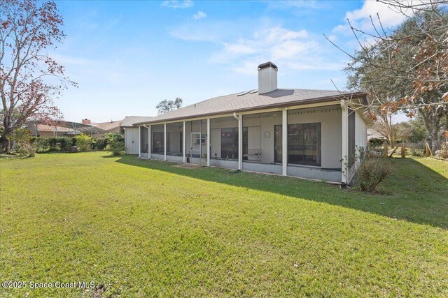 rear view of property with a yard and a sunroom