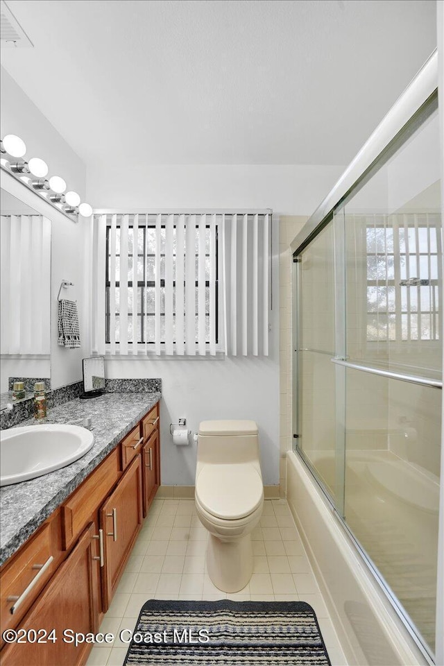 full bathroom with tile patterned flooring, vanity, toilet, and combined bath / shower with glass door