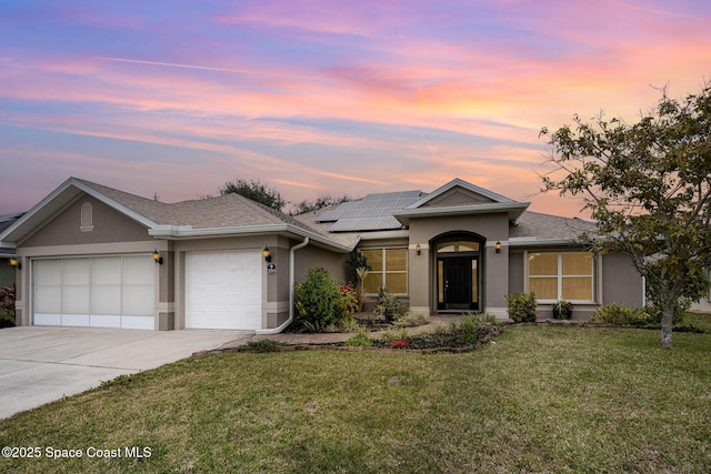 view of front of home featuring a lawn, solar panels, and a garage