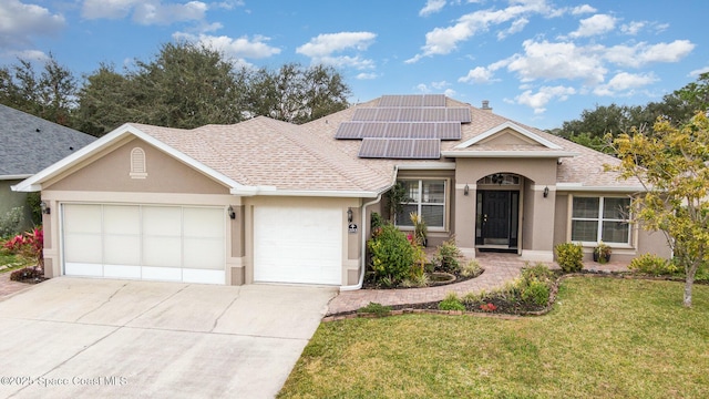 view of front of property featuring a garage, a front yard, and solar panels