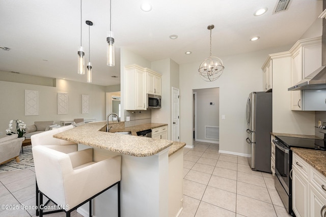 kitchen with a breakfast bar area, appliances with stainless steel finishes, wall chimney exhaust hood, light tile patterned flooring, and pendant lighting