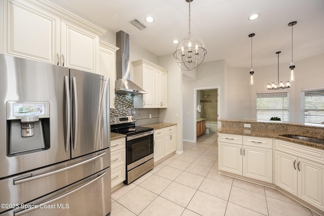 kitchen featuring an inviting chandelier, stainless steel appliances, dark stone counters, wall chimney range hood, and pendant lighting