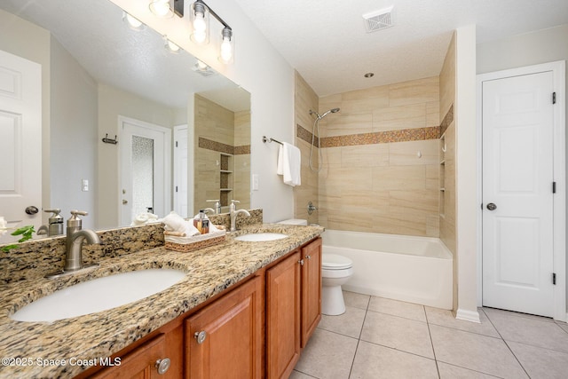 full bathroom featuring a textured ceiling, tiled shower / bath combo, tile patterned floors, vanity, and toilet