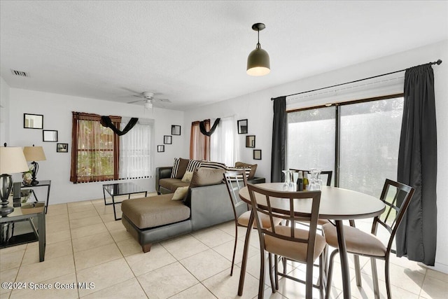 tiled dining room featuring ceiling fan and a textured ceiling