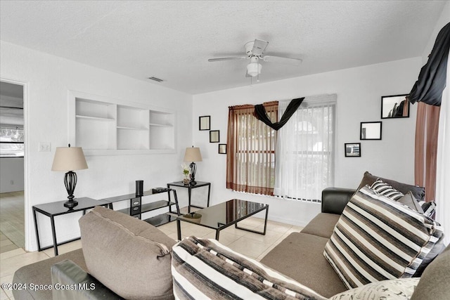 living room with ceiling fan, light tile patterned floors, and a textured ceiling