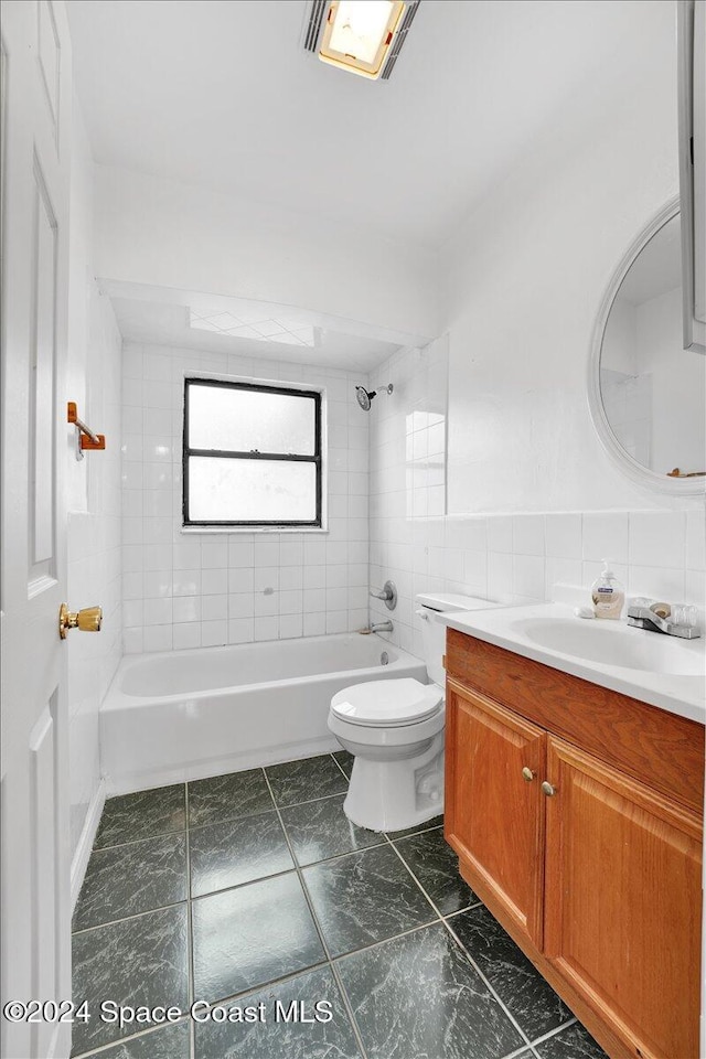 full bathroom featuring tile walls, vanity, tiled shower / bath combo, and toilet