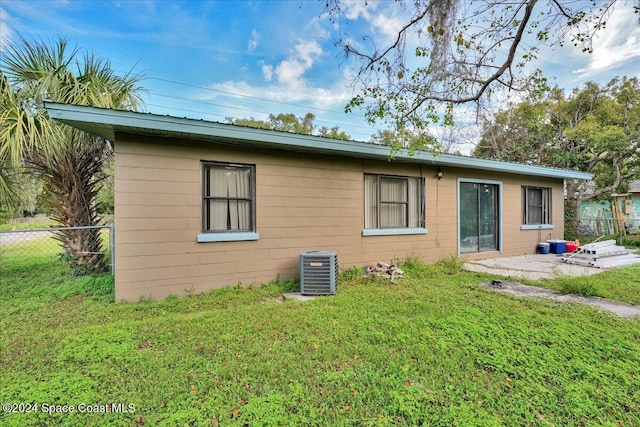 rear view of house featuring a lawn and cooling unit