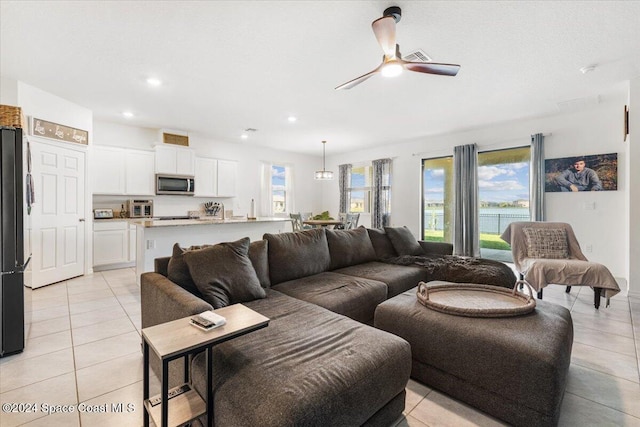 living room with ceiling fan, light tile patterned floors, and a healthy amount of sunlight