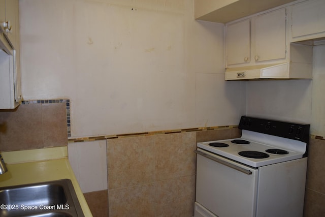 kitchen featuring white electric range oven, white cabinets, tile walls, and sink