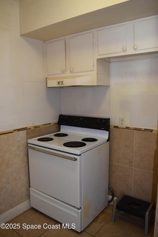 kitchen with white electric range oven, white cabinets, tile patterned floors, and tile walls